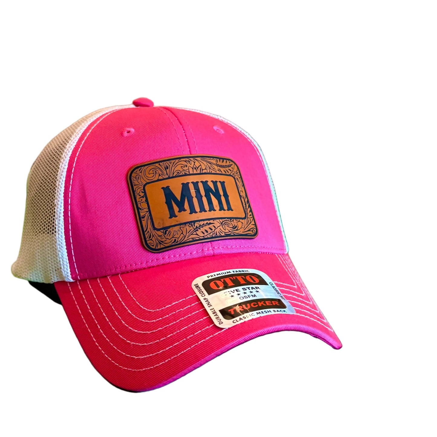 A pink and white trucker hat with a brown 'MINI' patch on the front.